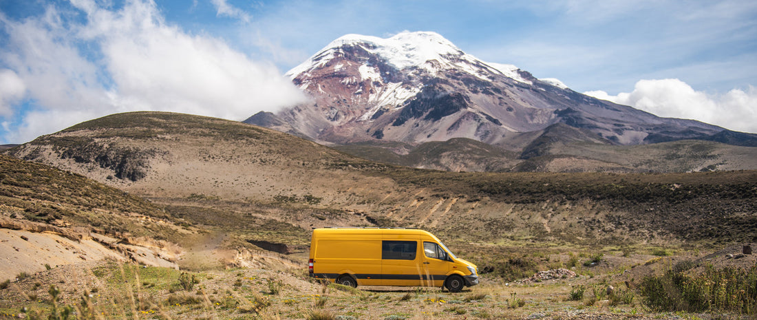 A yellow campervan, a snowy mountain peak in background