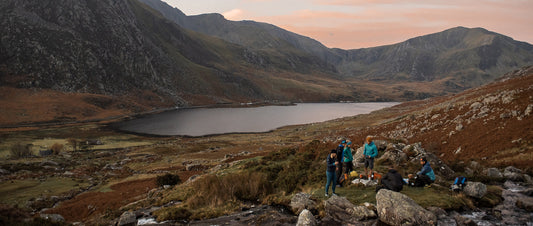 a group of friends hang out by a lake in the hills