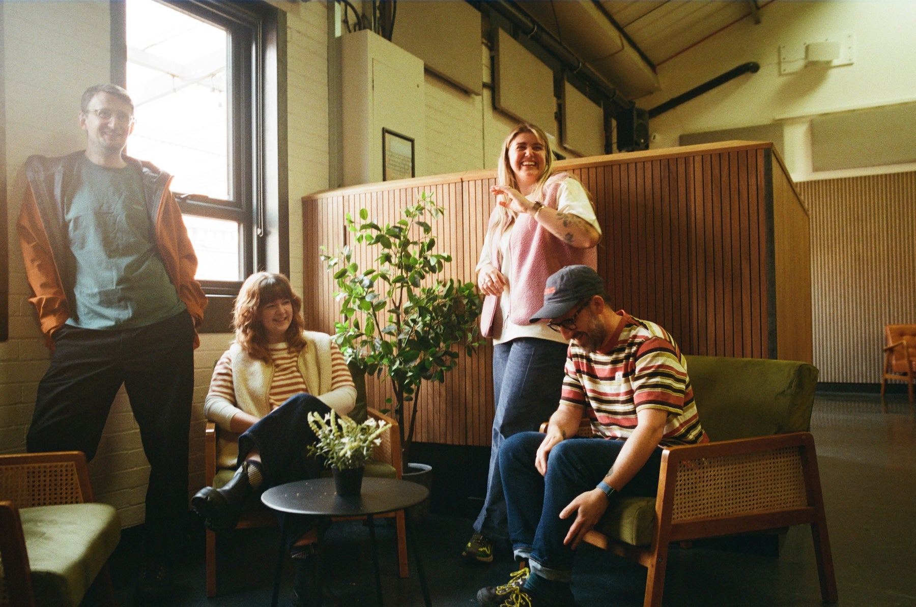 Group of people in a casual indoor setting with plants and furniture.
